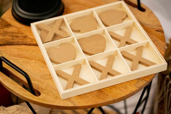 Love & kisses A wooden tic-tac-toe game with brown pieces in a grid pattern.